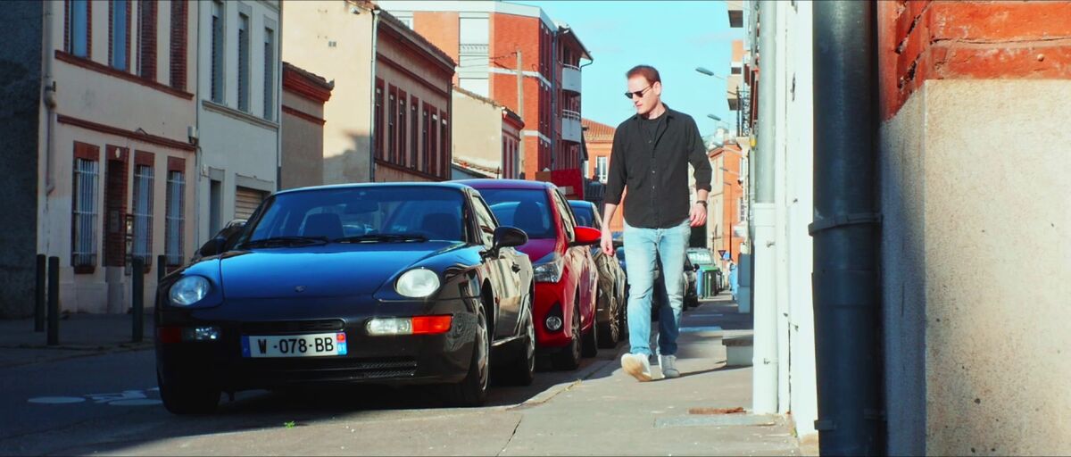 Un homme et des voitures dans une rue de Toulouse, dans Plein Gaz.